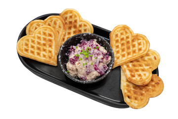 Heart-shaped waffles and a small bowl of a delicious fresh salad on a serving plate, a delicious and creative dish ready to be enjoyed. The presentation is simple and elegant