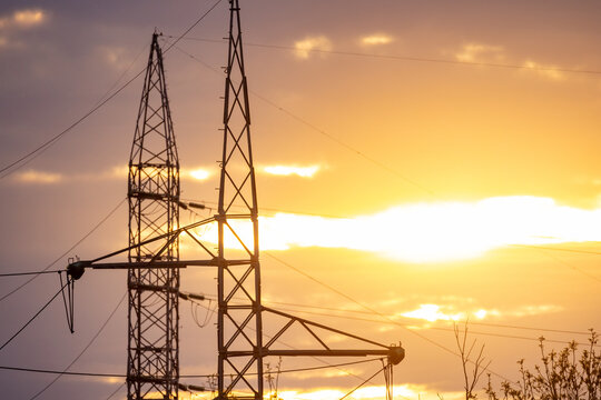 Golden sky over metallic structures, Rural scene featuring sunset behind transmission towers and silhouetted field