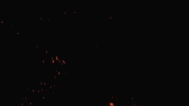 Realtime shot of fire flames with sparks rising of campfire over black background