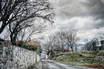 Moody winter mountain village street under dramatic cloudy sky in Greece