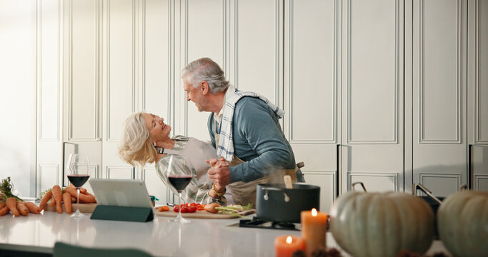 Cooking, dance and old couple in kitchen for love, supper and online recipe for bonding in home. Wine, retirement and senior man and woman for meal prep, tablet and support for anniversary dinner - Powered by Adobe