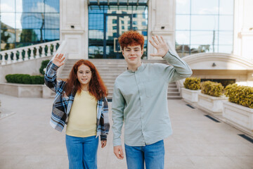 Ginger brother and redhead sister waving hand gesture in the city