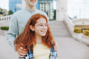 Ginger-haired teenage brother with redhead sister outdoors in the city