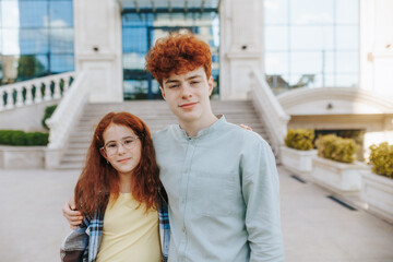 Redhead boy and girl with glasses looking at camera outdoors
