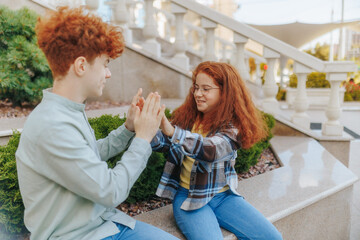 Ginger-haired boy and girl spending playful time together on stone stairs