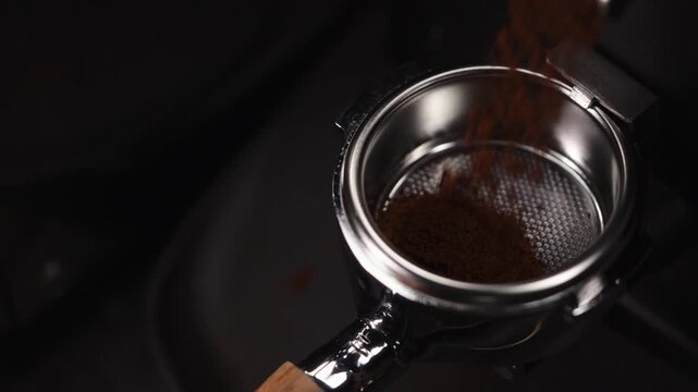 Slow motion ground coffee pouring into portafilter from grinder