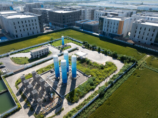 Industrial gas facility with blue towers, pipes, and power lines in rural area.