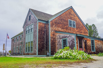 Traditional wooden shingle building with American flag and autumn flowers, Portsmouth, New Hampshire, classic New England setting.
