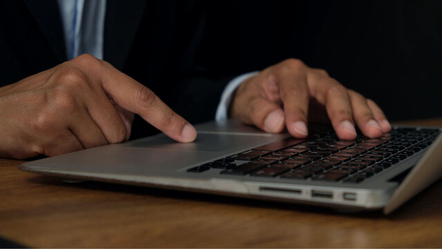 Close up of businessman hands typing on laptop keyboard, working in office environment, focused on business growth and global communication