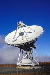 White satellite dish telescope poised above volcanic summit clouds