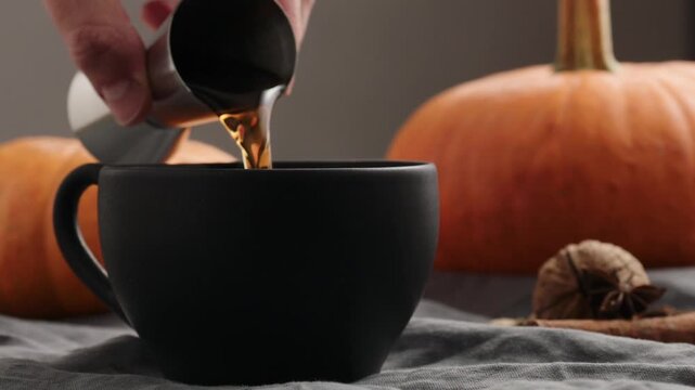 Slow motion making spiced pumpkin latte in black cup, pour spiced syrup