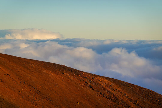 Sunlit volcanic slope and rolling clouds at high mountain viewpoint