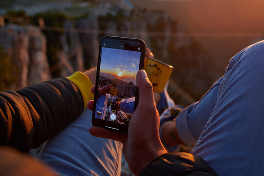 A man is sitting, holding a phone in his hands, taking pictures. High quality photo