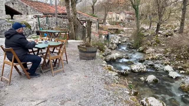 Hombre tomando caf&eacute; al lado del r&iacute;o en Bulnes, Asturias
