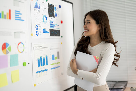 Happy businesswoman analyzing data presentation on whiteboard