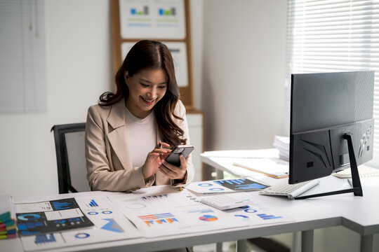 Asian businesswoman using smartphone at office desk