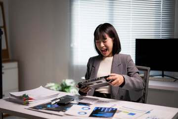 Businesswoman playing handheld console, excited during work break