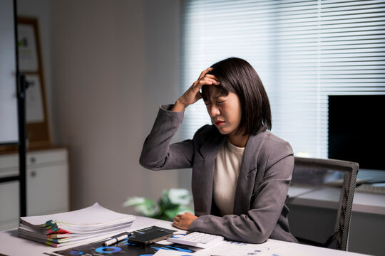 Businesswoman experiencing headache from working overtime at office