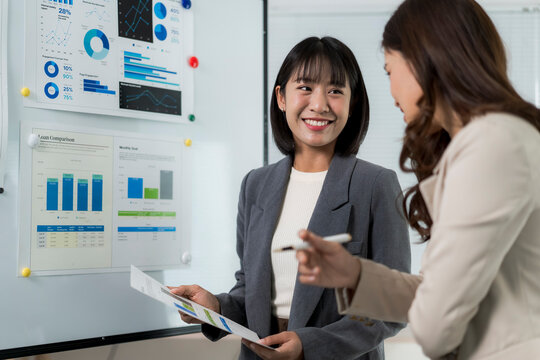 Asian businesswomen discussing financial data during office meeting