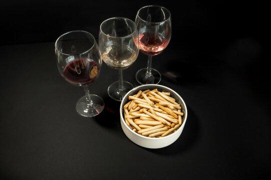Small breadsticks on white plate on black background
