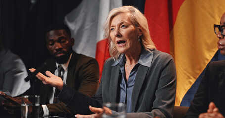 Politics, group or woman with speech at press conference for media debrief, global summit or opinion. Government panel, forum and mature person with update on policy decision and diplomatic relations
