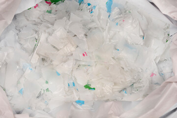 A high-angle, full-frame close-up shows a large pile of shiny, brittle, and partially degraded...