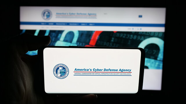 Stuttgart, Germany - 11-02-2025: Person holding cellphone with logo of cyber security and infrastructure agency CISA on screen in front of webpage. Focus on phone display.