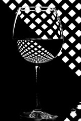 Still life with a glass with liquid on a grid background