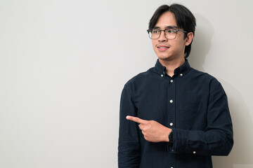 Portrait of handsome young Asian Thai man wearing eyeglasses showing copy space with hand gesture