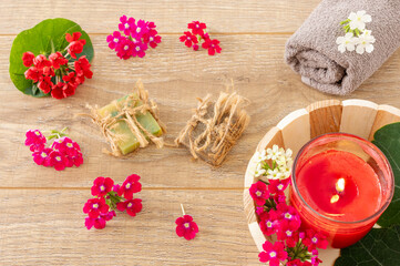 Towel with body care products and verbena flowers on the wooden background.
