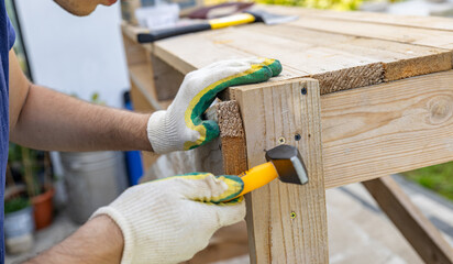 Close-up. Carpenter with hammer and nails fixes a wooden board. Construction industry, do it...