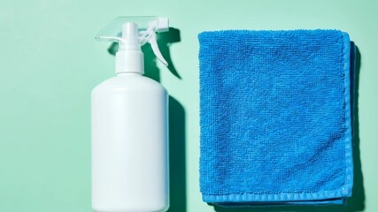 White spray bottle and blue cleaning towel on a green background. Simple home cleaning tools for domestic use and hygiene. - Powered by Adobe