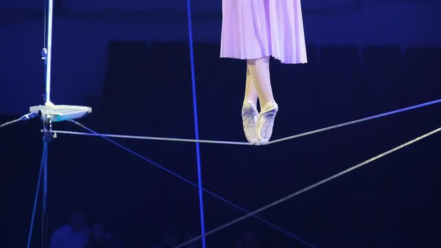 Close-up of an aerial acrobat walking on a tightrope on tiptoes. The image captures the performer balance and elegance, showcasing the precision and grace needed for this high-flying act