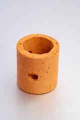 A single, upright cylindrical object made of porous terracotta clay, commonly used as a planting weight or submerged pot for anchoring aquatic plants in an aquarium.