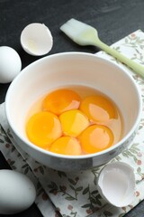 Raw eggs, yolks and brush on black table, closeup