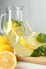 Fresh lemonade in glasses, jug, lemons and mint on white table, closeup