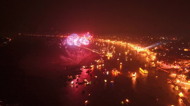 A breathtaking drone image capturing fireworks exploding above the glowing ghats of Kashi during Dev Deepawali. The Ganga River reflects the lights, symbolizing divine joy and devotion.