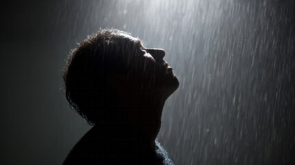 Glistening rain cascades over introspective silhouette of South Asian man, capturing serene monsoon meditation and World Water Day
