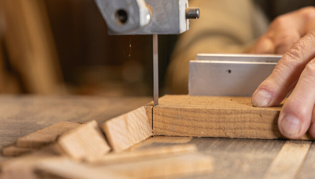 Gros plan sur un menuisier d&eacute;coupant une planche de bois &agrave; la scie &agrave; ruban.