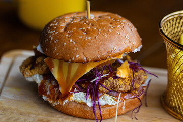 A close-up of a delicious crispy chicken burger with melted cheese, fresh vegetables, and sauce on a sesame bun, served with golden fries. Perfect for fast food menus, restaurant ads, & food delivery