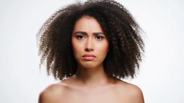 A portrait of a woman looking sad. She has curly hair and looks straight at the camera. She's expressing her sadness. Stock Video