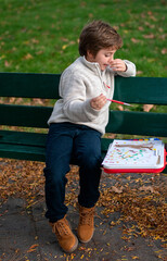 Portrait of a 7-year-old boy drawing in the park on an autumn day