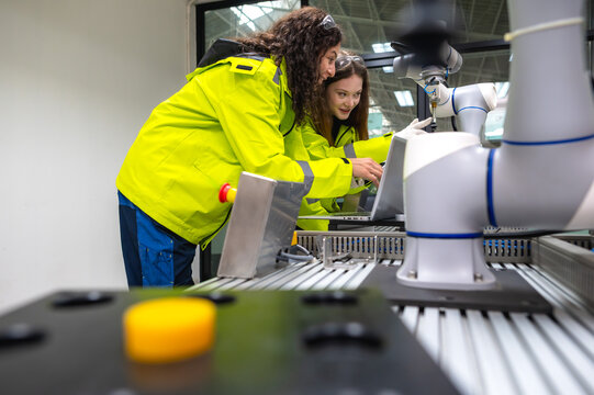 Two female robotic engineer team working with artificial intelligent robot arm in learning center