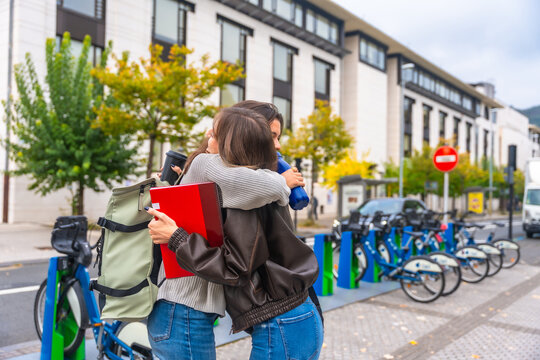 Students meeting hug on campus street returning to classes