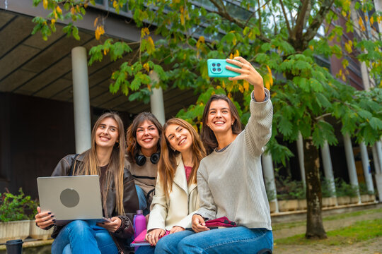 Happy students taking outdoor campus selfie with laptop - Powered by Adobe