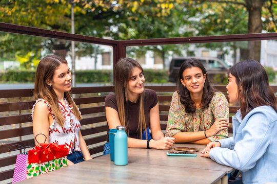 Group of young women friends socializing and talking at outdoor cafe