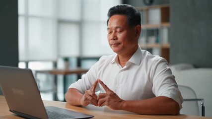 A focused man is thoughtfully working with a laptop. He sits at a desk with his hands clasped, exuding concentration Stock Video - Powered by Adobe
