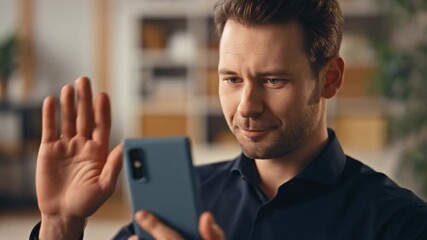 A man greets during a video call on a smartphone, waving hand happily Stock Video - Powered by Adobe
