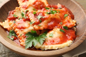 Delicious ravioli with tomato sauce and parsley on wooden table, closeup