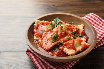 Delicious ravioli with tomato sauce and parsley on wooden table, closeup